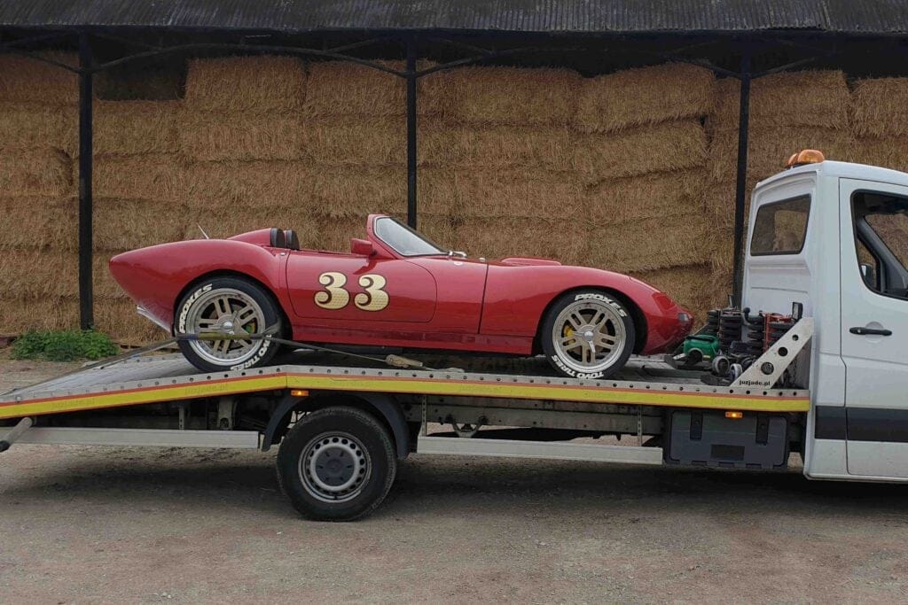 classic car recovery London — red vintage roadster secured on a flatbed tow truck with soft straps, ready for transport