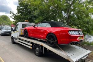 Emergency towing service London – red Ford Mustang secured on a flatbed tow truck by London Auto Towing
