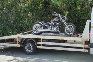 Motorbike recovery London — custom motorcycle secured with soft straps on a flatbed tow truck