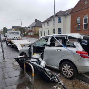Accident recovery in London — heavily damaged car with police tape being prepared for loading onto a flatbed