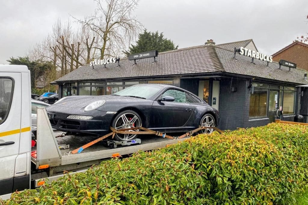 Car towing service near me in London — Porsche on flatbed tow truck outside Starbucks