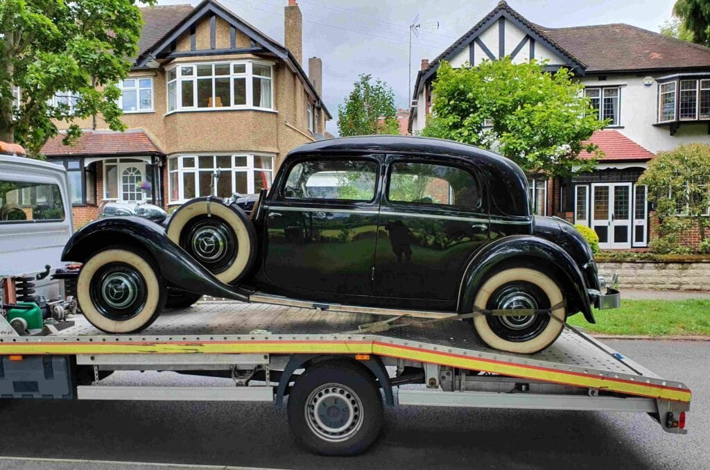 Classic car towing service London — black vintage car on flatbed tow truck