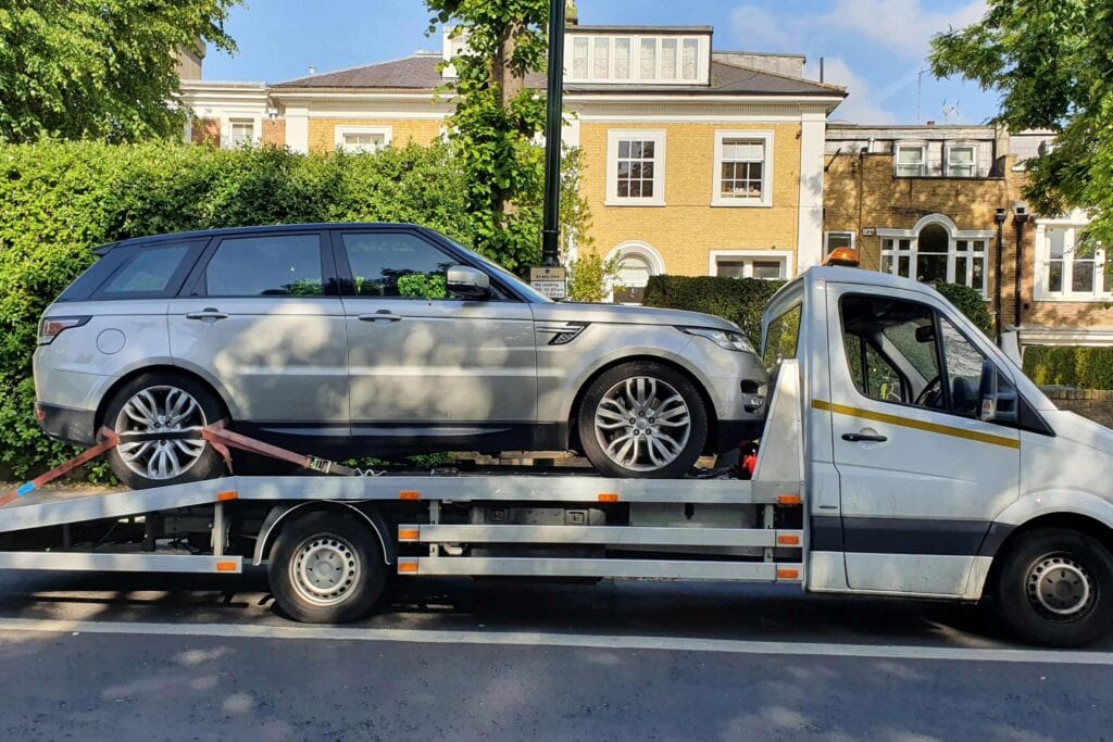 Flatbed tow truck in London transporting a silver Range Rover during an emergency car recovery