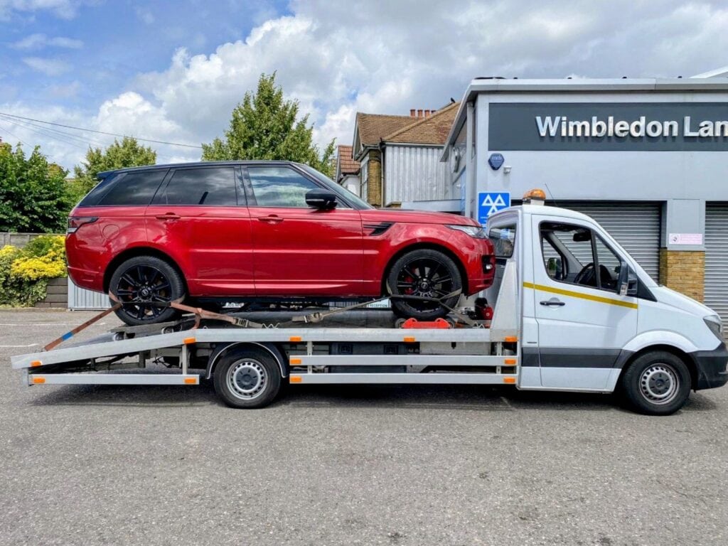 Flatbed tow truck in London transporting a red Range Rover — local towing service London