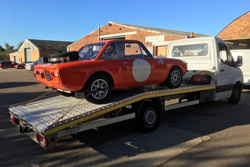 Long distance car towing service in London with flatbed tow truck transporting a classic car