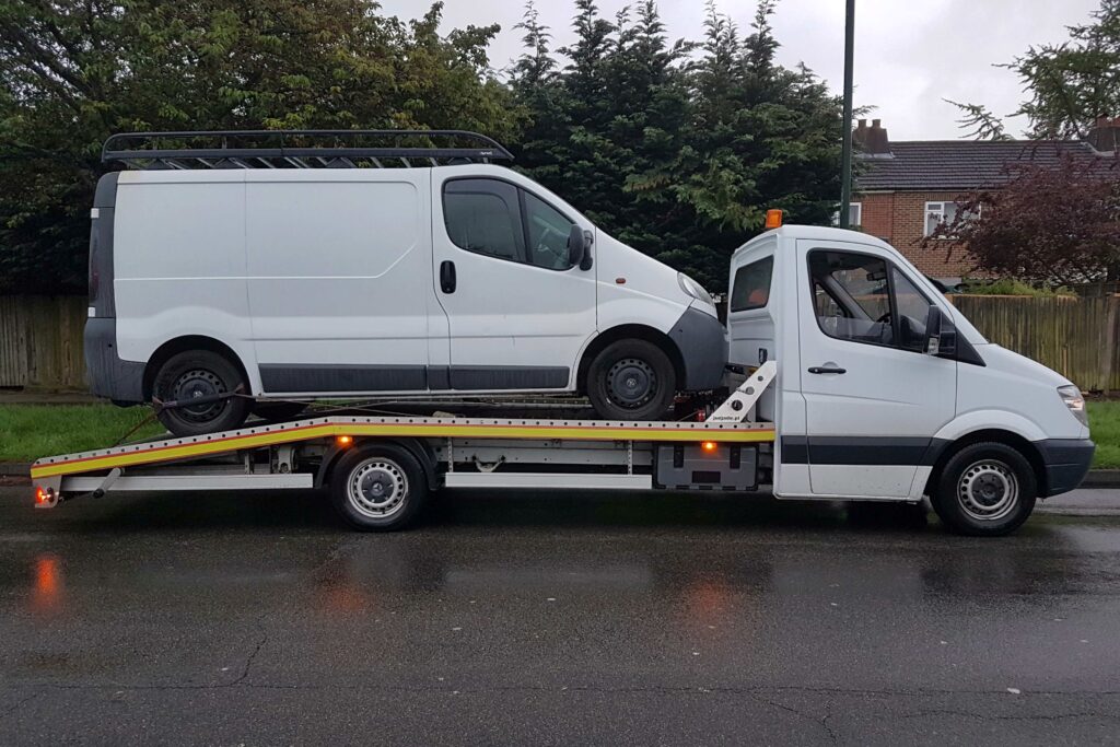 Van towing service London — flatbed tow truck transporting a white panel van