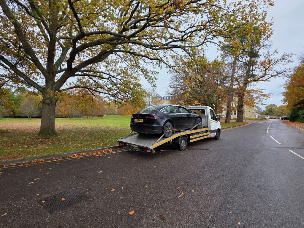 Tesla loaded on flatbed tow truck during electric vehicle breakdown recovery in London.