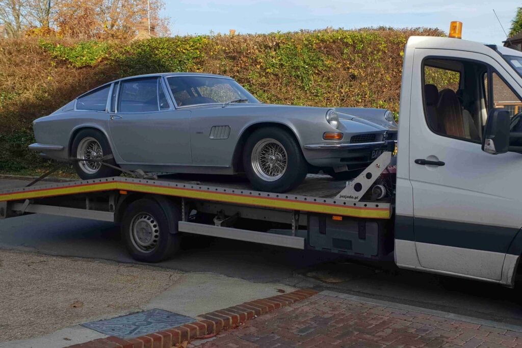 Classic car recovery in London — silver coupé secured on a flatbed tow truck.