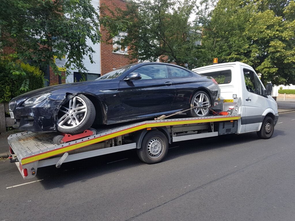 Accident car recovery using wheel skates and flatbed towing service