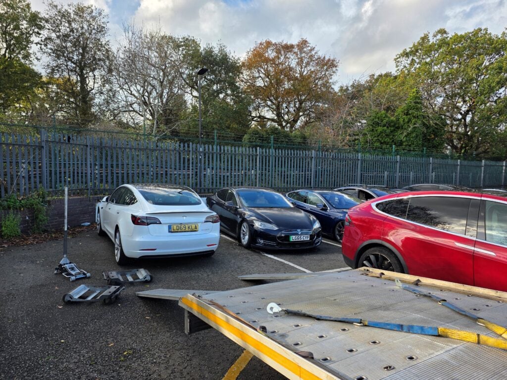 Multiple Tesla electric vehicles with wheel skates and flatbed ramp during electric car recovery by London Auto Towing.