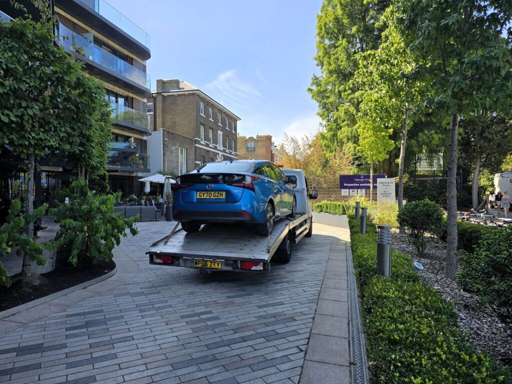 Hybrid Toyota Prius on a flatbed recovery truck during an electric vehicle recovery job in London.