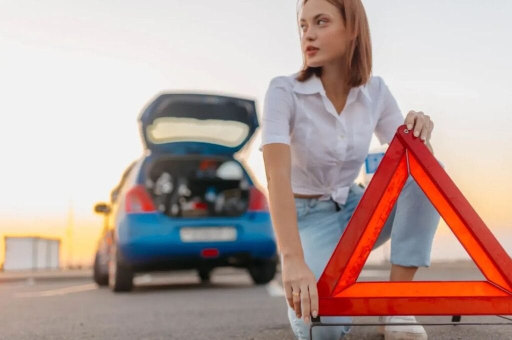 Roadside assistance scene with warning triangle placed beside a broken-down car