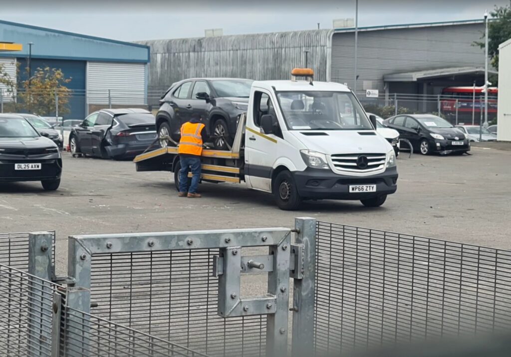 Police compound recovery with flatbed tow truck collecting a vehicle under insured towing service