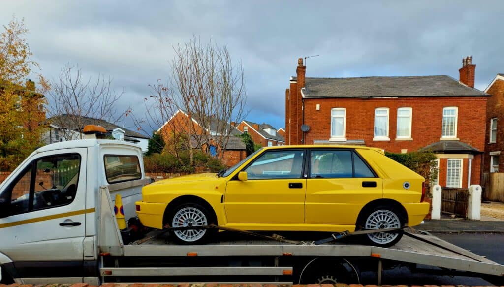 local towing service with flatbed tow truck loading yellow car after breakdown recovery