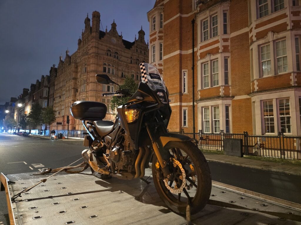 Motorbike recovery and motorcycle towing service loaded on flatbed tow truck at night
