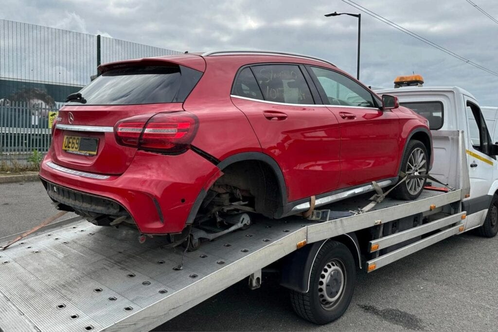 Damaged Mercedes SUV loaded on our flatbed tow truck during a scrap car collection