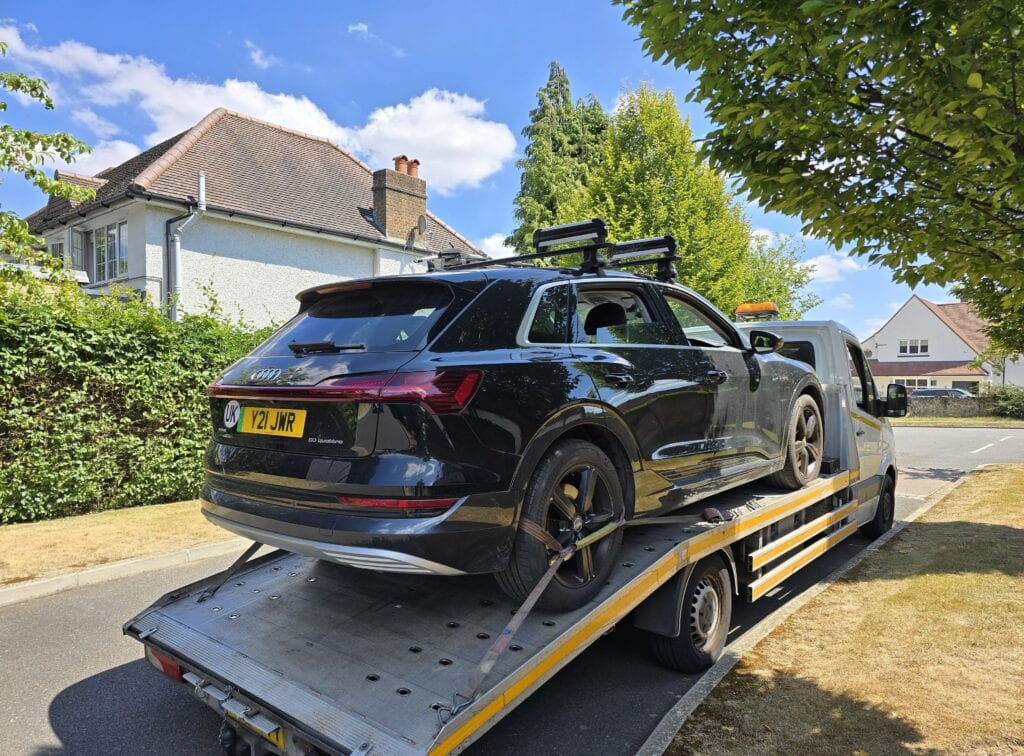 Audi e-tron electric SUV recovered on a flatbed tow truck after an auxiliary battery issue when jump start support did not work in London