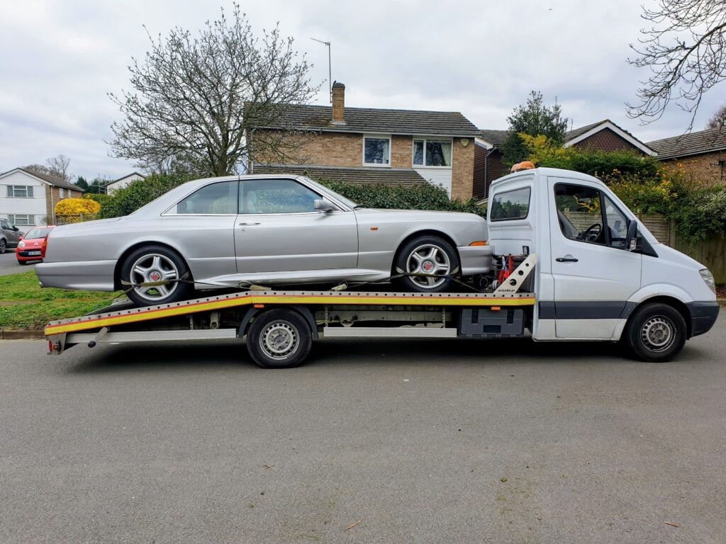 Silver Bentley Continental loaded onto a flatbed recovery truck for luxury car towing services.