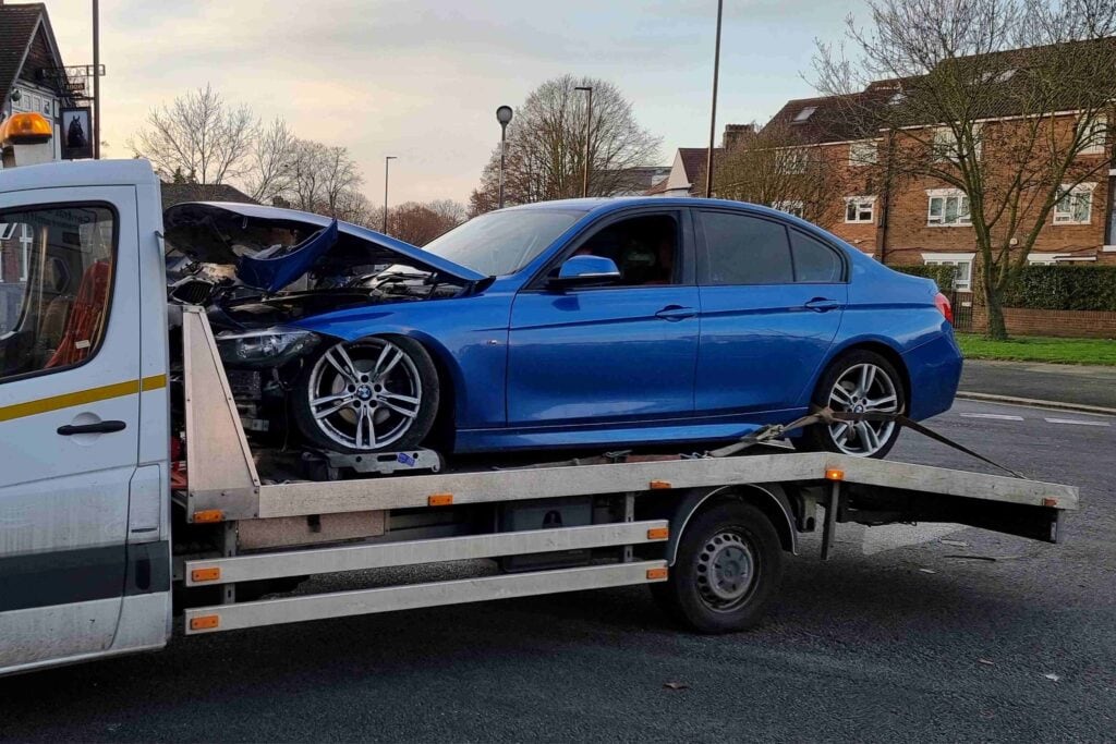BMW 3 Series accident recovery on flatbed tow truck using wheel skates after suspension damage in London