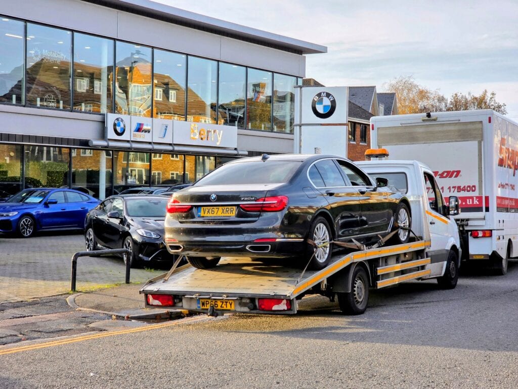 Black BMW 7 Series 730d on flatbed recovery truck being delivered to Berry BMW for annual service.