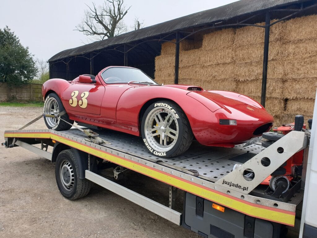 Flatbed towing service truck recovering a classic red sports car using soft straps for safe high value car recovery