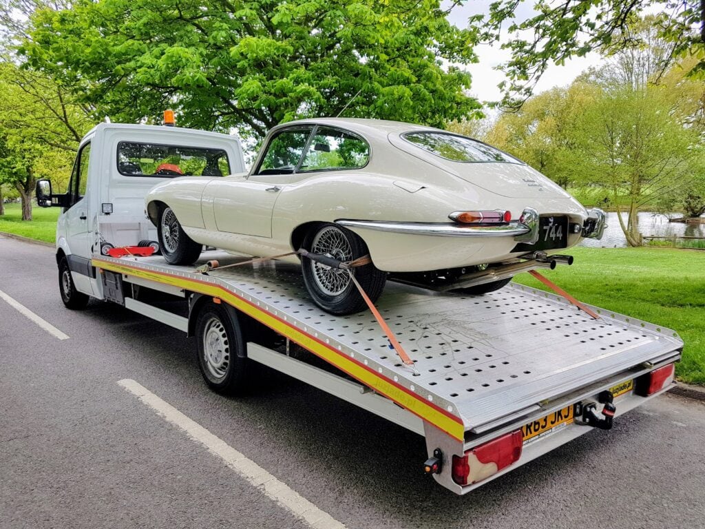 Classic Jaguar E-Type secured on a flatbed recovery truck during professional classic car recovery in London.