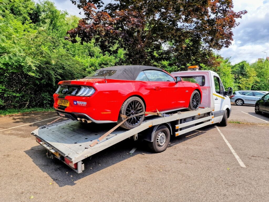 High value car recovery using flatbed towing service in London, red Ford Mustang safely secured and transported.