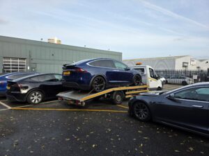 High value electric car recovery for a blue Tesla Model X loaded on our flatbed tow truck at a service centre in London.