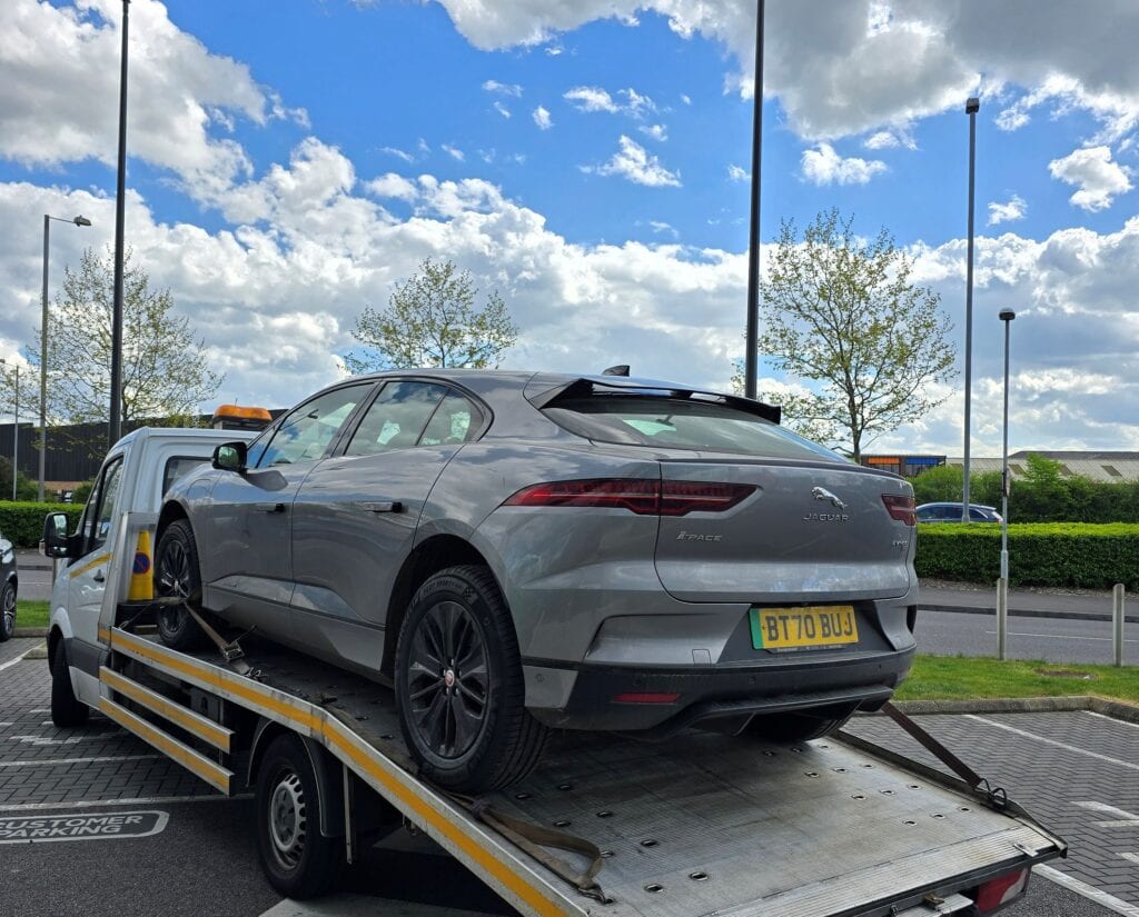 Jaguar I-PACE electric SUV recovered during an emergency roadside rescue and secured on a flatbed recovery truck in London