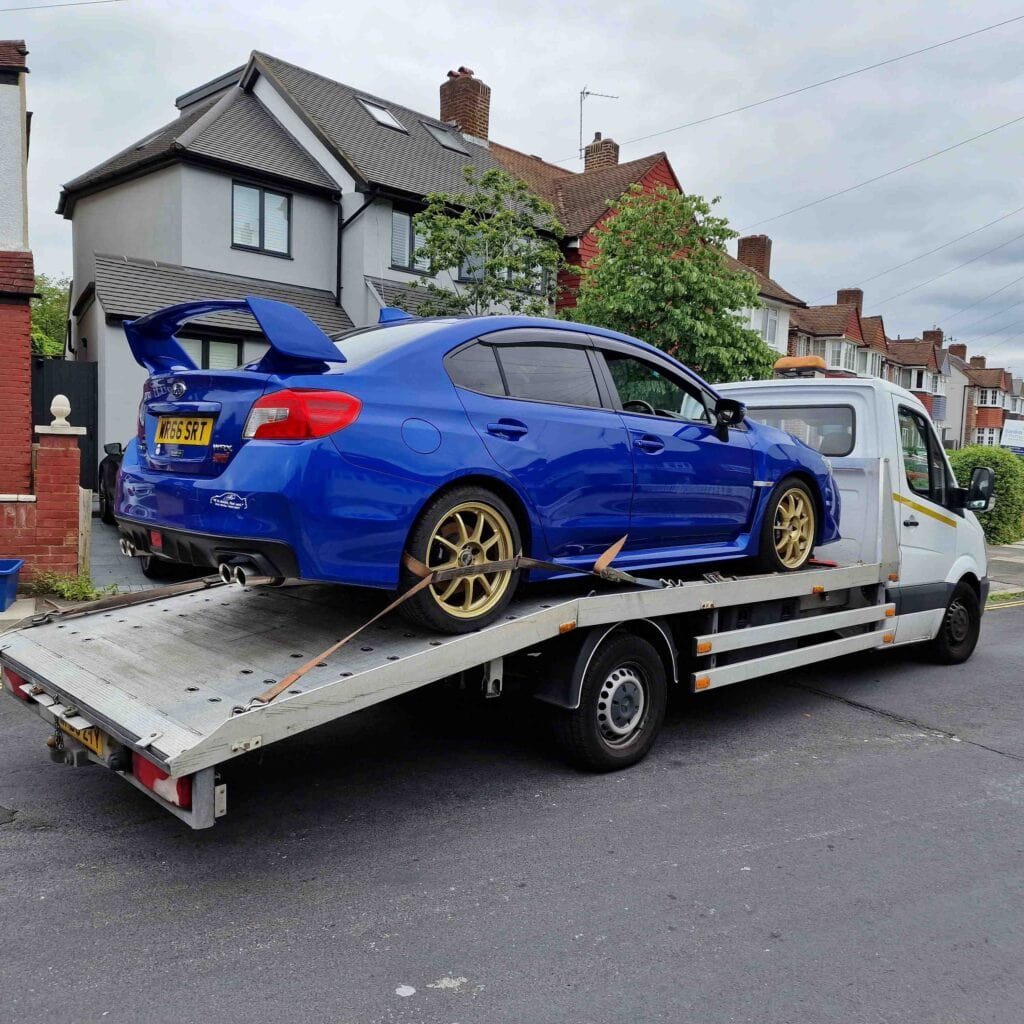 Flatbed towing service transporting a blue Subaru WRX STI sports car in London