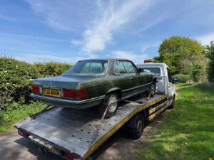 Classic Mercedes 450 SLC secured on our flatbed tow truck during high value car recovery on a country road near London.