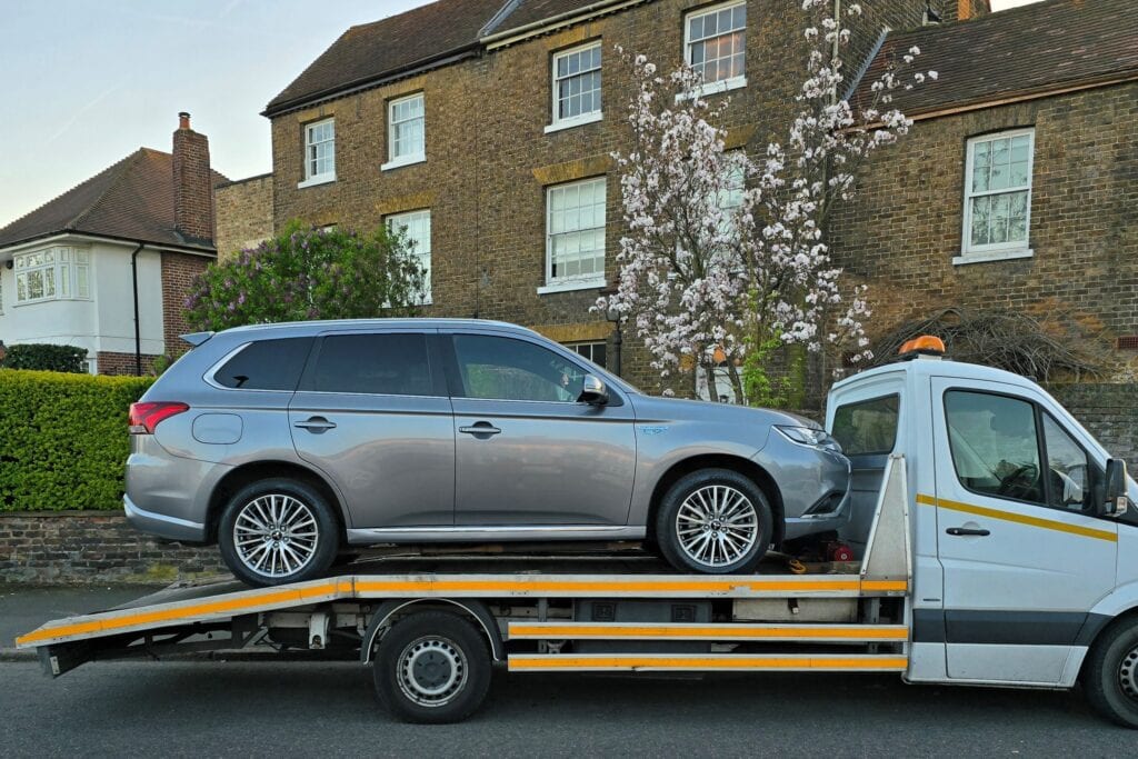 Mitsubishi Outlander PHEV plug-in hybrid transported on a flatbed recovery truck after auction purchase in London