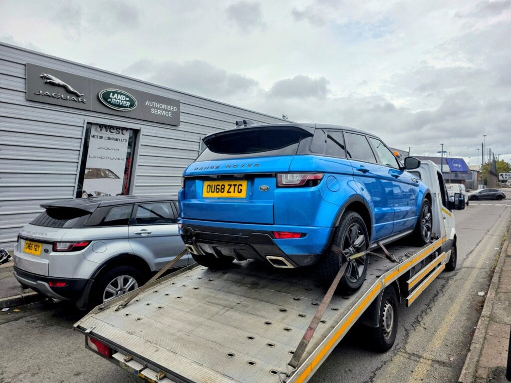 Range Rover Evoque non runner loaded onto a flatbed tow truck outside authorised Land Rover service centre in London