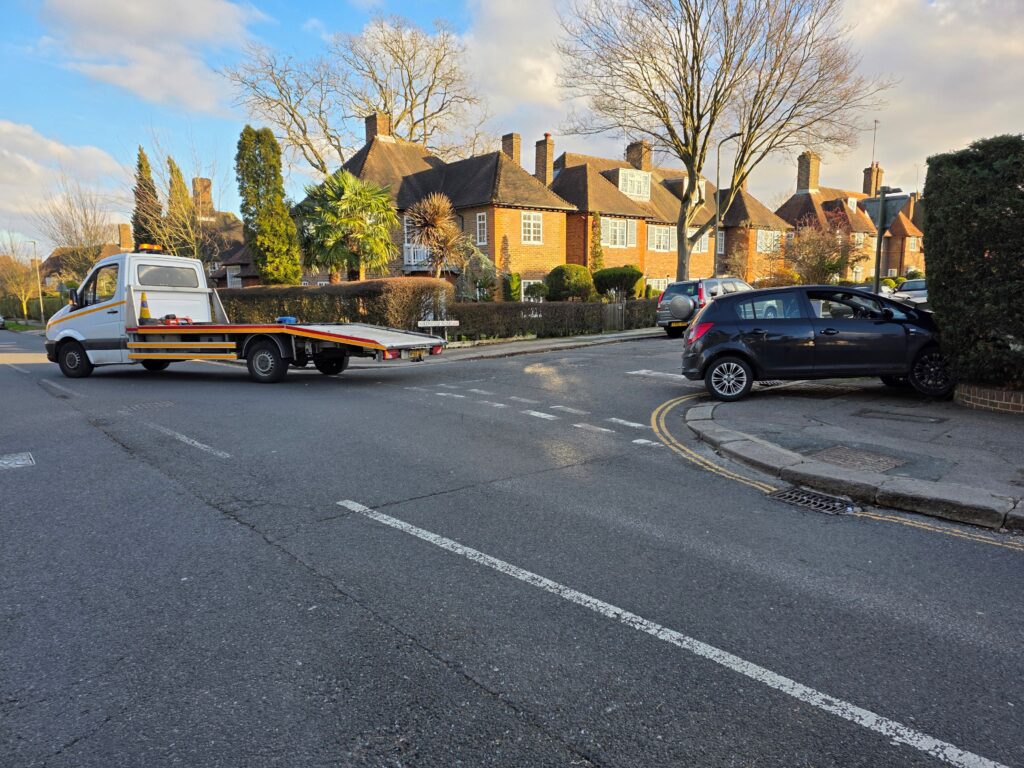 Roadside accident scene with recovery truck arriving to assist damaged vehicle in London