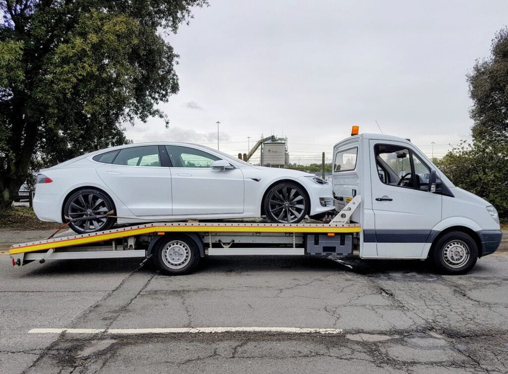 White Tesla Model S loaded onto a flatbed recovery truck for delivery to Southampton Port for shipping to Cyprus.