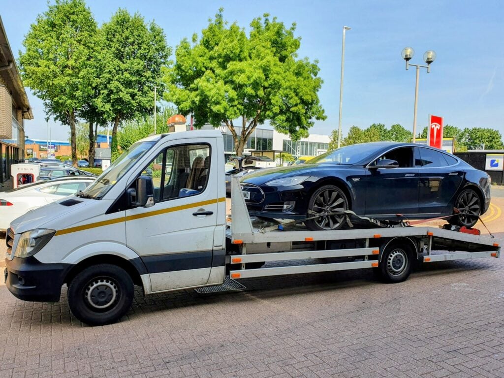 Tesla loaded using wheel skates after a software issue stopped tow mode from activating, secured for safe transport in London.