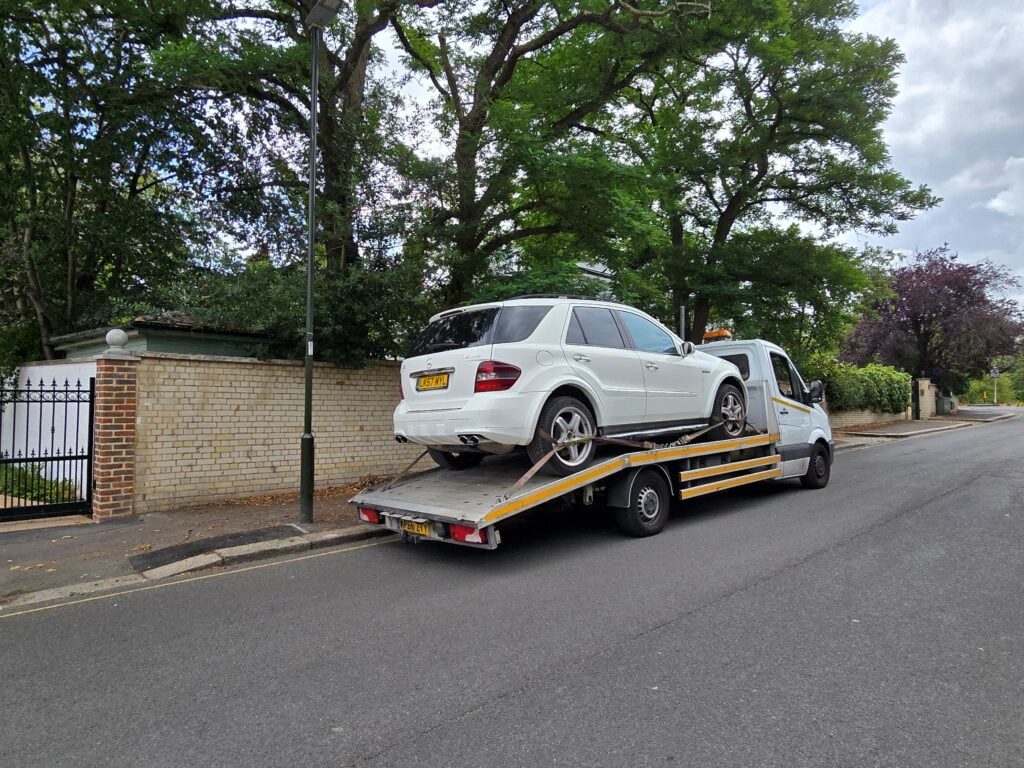 Flatbed tow truck collecting a white Mercedes SUV as part of our we buy any cars and vans service in London.