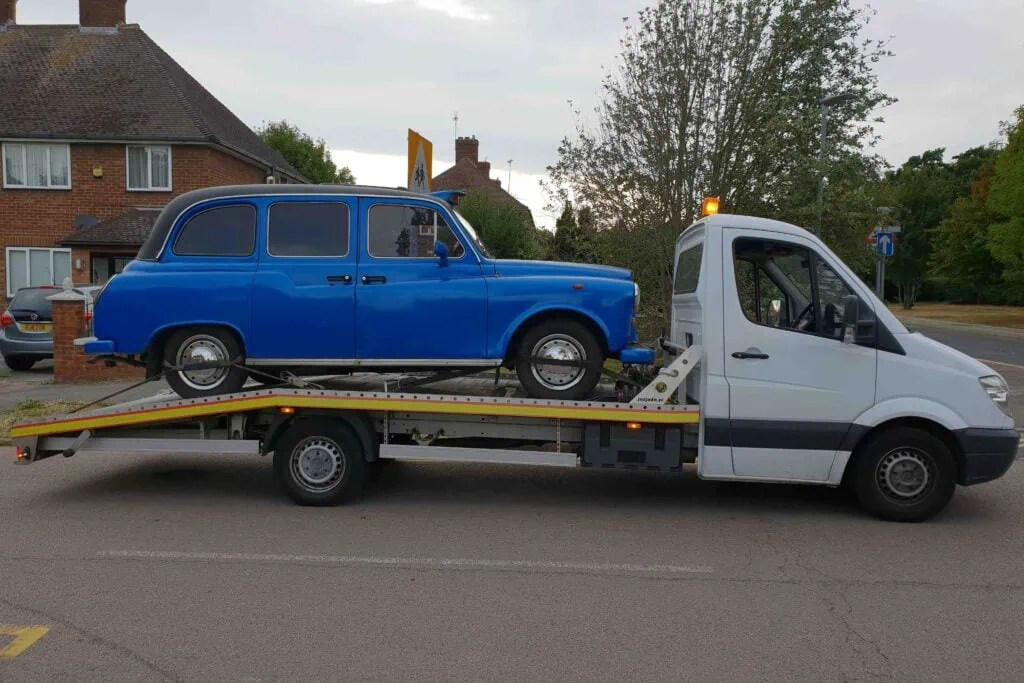 Classic London taxi loaded onto a flatbed recovery truck for safe vehicle transport in London.