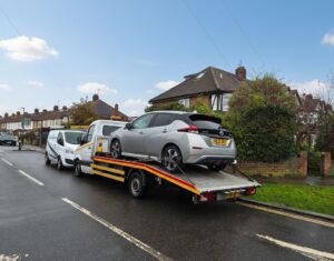 Nissan Leaf secured on flatbed tow truck during local flatbed towing service Richmond on residential road.
