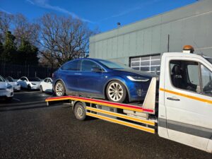 Specialist electric car recovery Richmond service loading a blue Tesla Model X onto a flatbed tow truck using EV-safe loading methods.