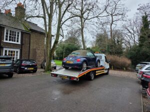 Professional emergency car towing service Richmond loading a blue Volkswagen Beetle cabriolet onto a flatbed tow truck.