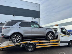 Land Rover Discovery secured on flatbed tow truck during insured police compound recovery service
