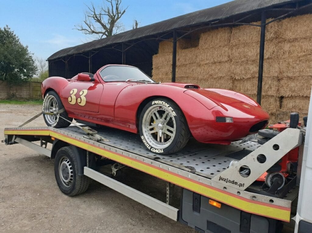 Classic red sports car secured on flatbed recovery truck during professional car recovery in Twickenham