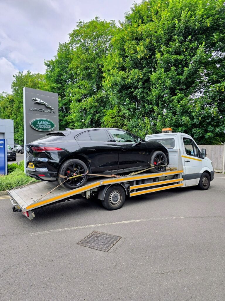 Flatbed car recovery Richmond upon Thames transporting Jaguar I-PACE outside Jaguar Land Rover dealership