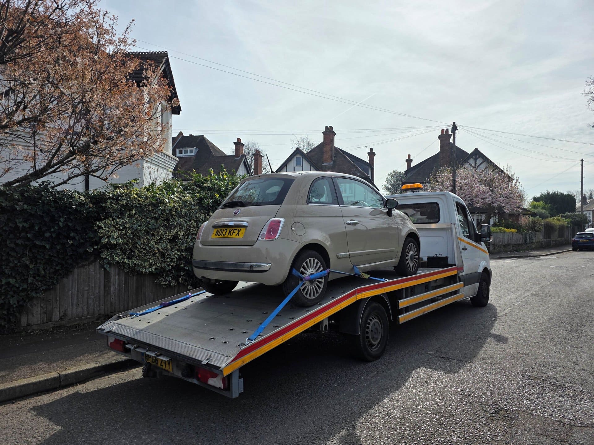 Police compound car recovery transporting seized Fiat 500 using flatbed recovery truck in London