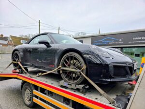 Black Porsche 911 loaded using professional wheel skates for safe accident recovery in Kingston.