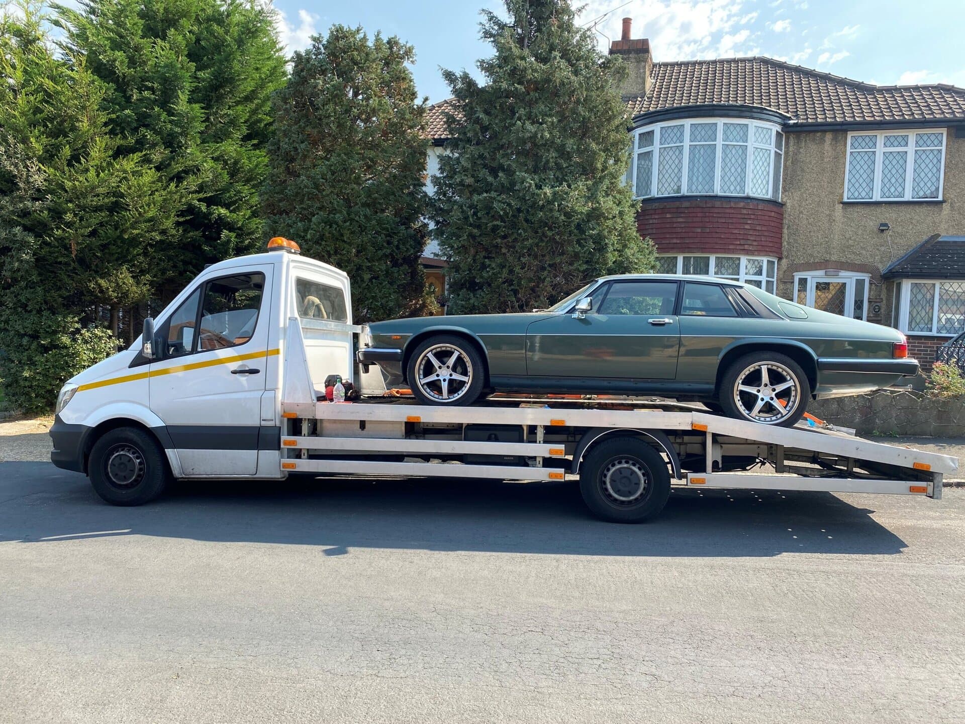 Classic Jaguar recovered on flatbed tow truck during professional car recovery Twickenham