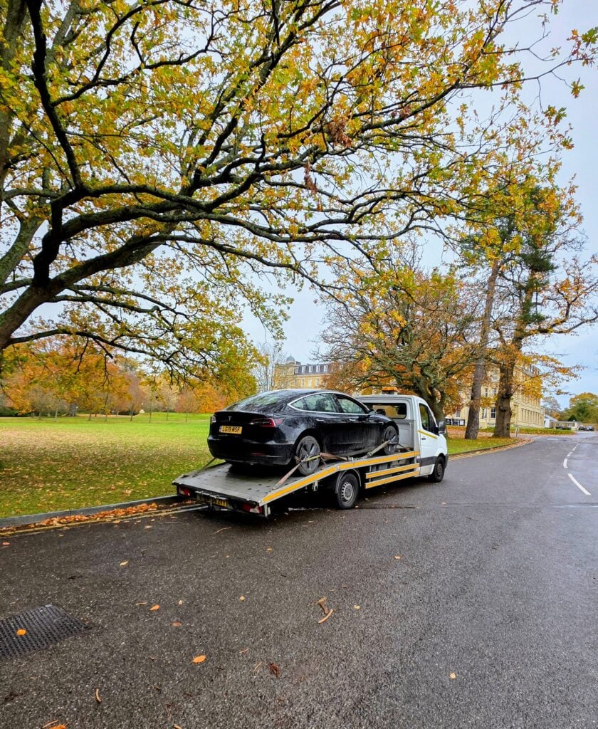 Professional electric car recovery in Twickenham showing a black Tesla Model 3 safely secured with soft-tie straps on a flatbed recovery truck.