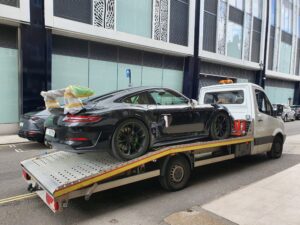 Emergency car recovery Twickenham featuring a black Porsche 911 GT3 RS secured on a professional white flatbed recovery truck for safe transport.