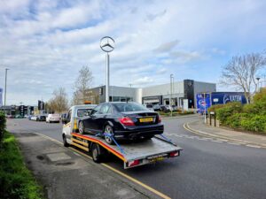 Expert impound car recovery of a black Mercedes C250 from Heathrow police compound using a flatbed tow truck for professional vehicle release in London.